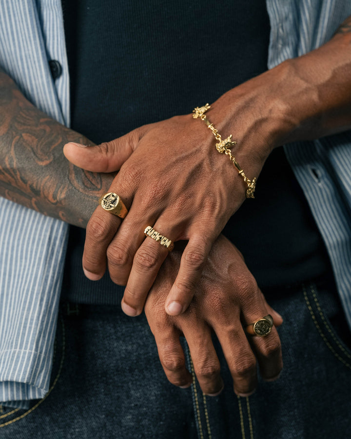 dog and dagger signet ring in gold and fuck ‘em ring in gold and dog & dagger bracelet in gold and smoking girl ring in gold model photograph